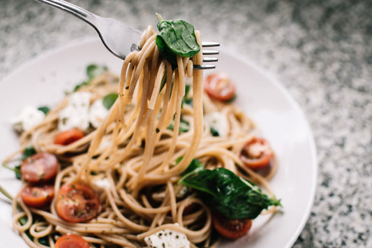 A plate of pasta with tomatoes and leafy greens