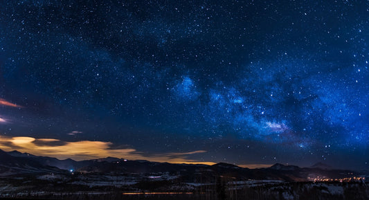 A star-filled night sky above dark mountain silhouettes